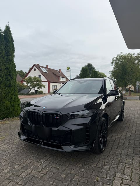 Schwarzer BMW X5 schräg von vorn, der Lack glänzt